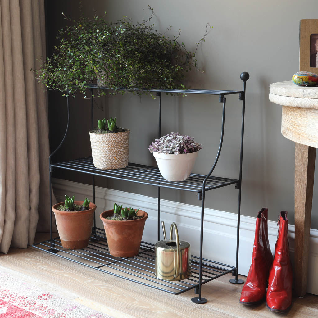 Elegance Tiered Plant Stand in Matt Black with plant pots and watering can on it