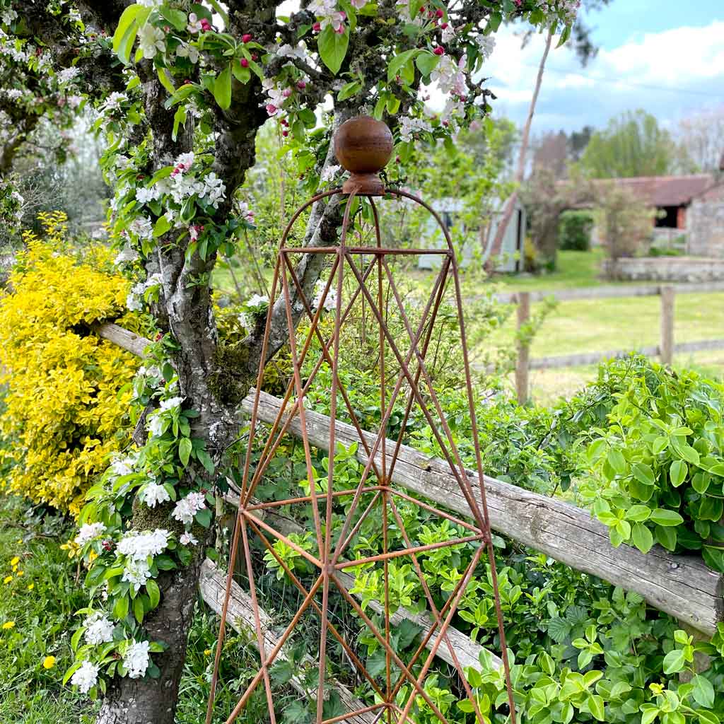 rustic garden obelisk next to fence in garden