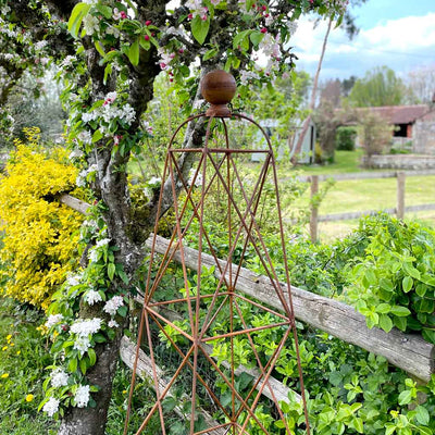 rustic garden obelisk next to fence in garden
